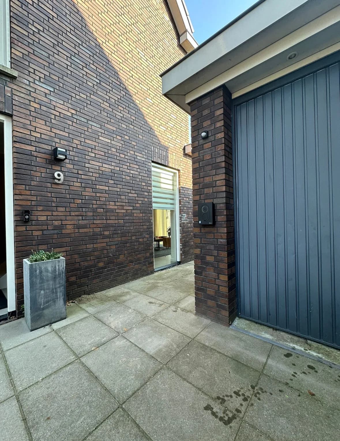 Laadstation aan de gevel naast een garagedeur, met de kabel netjes opgehangen