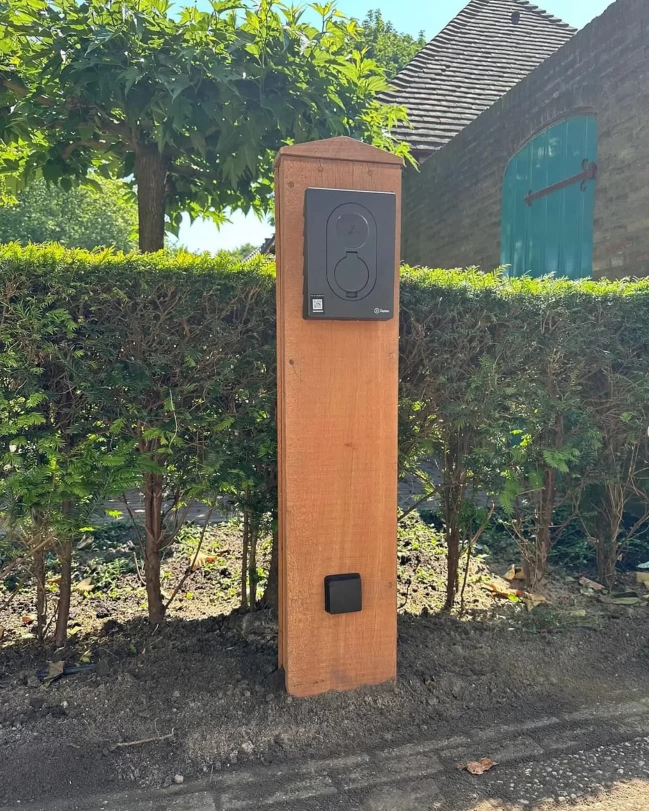 Laadstation op een staander in een tuin, met de bestrating weer dichtgelegd
